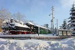 Die verschneite Lok der ehemaligen Schmalspurbahn mit Wagon steht auf dem stillgelegten Gleis mit Signalanlage 